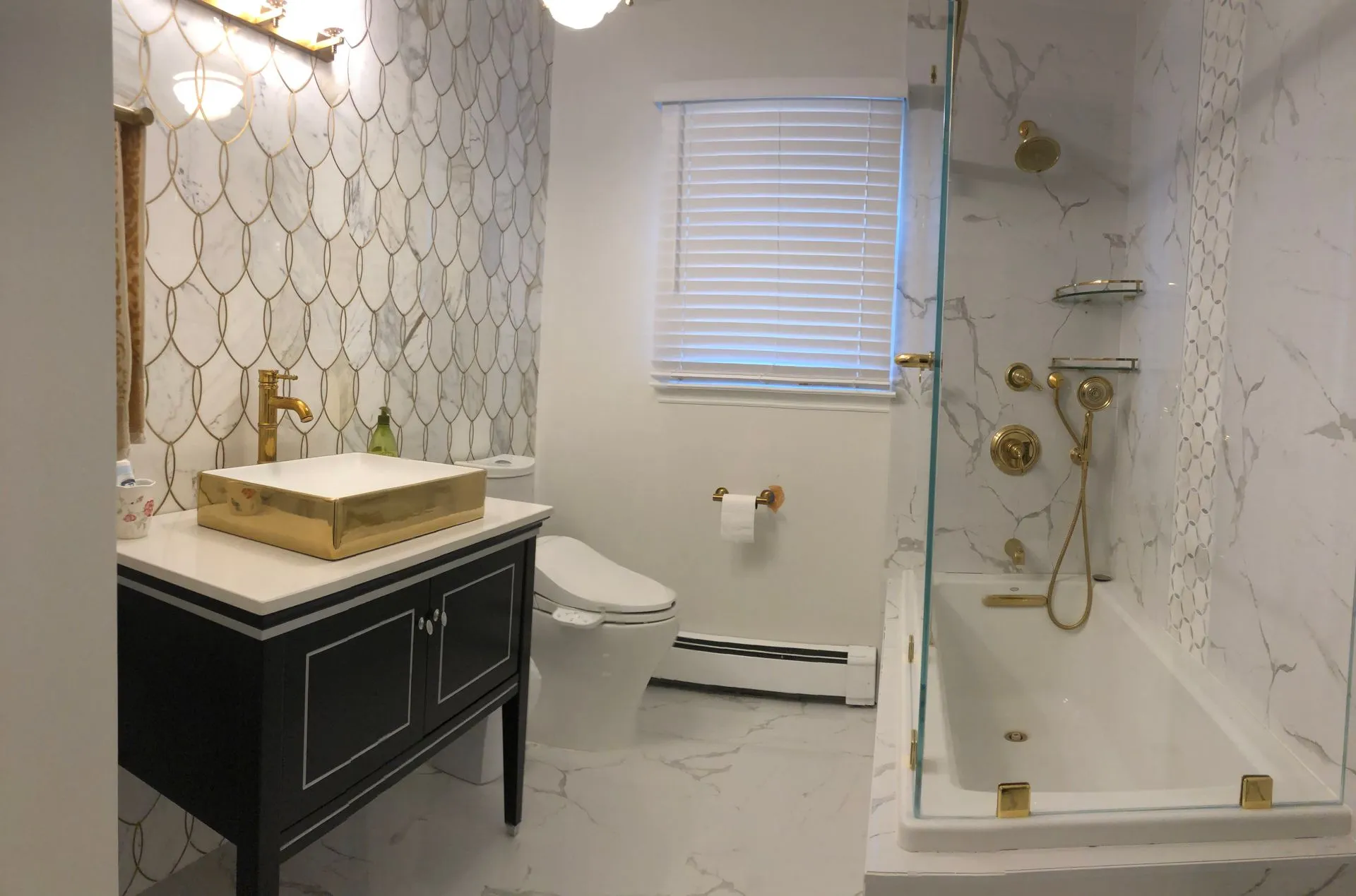 Elegant bathroom with gold fixtures, marble tile and glass shower enclosure - NJ bathroom remodel