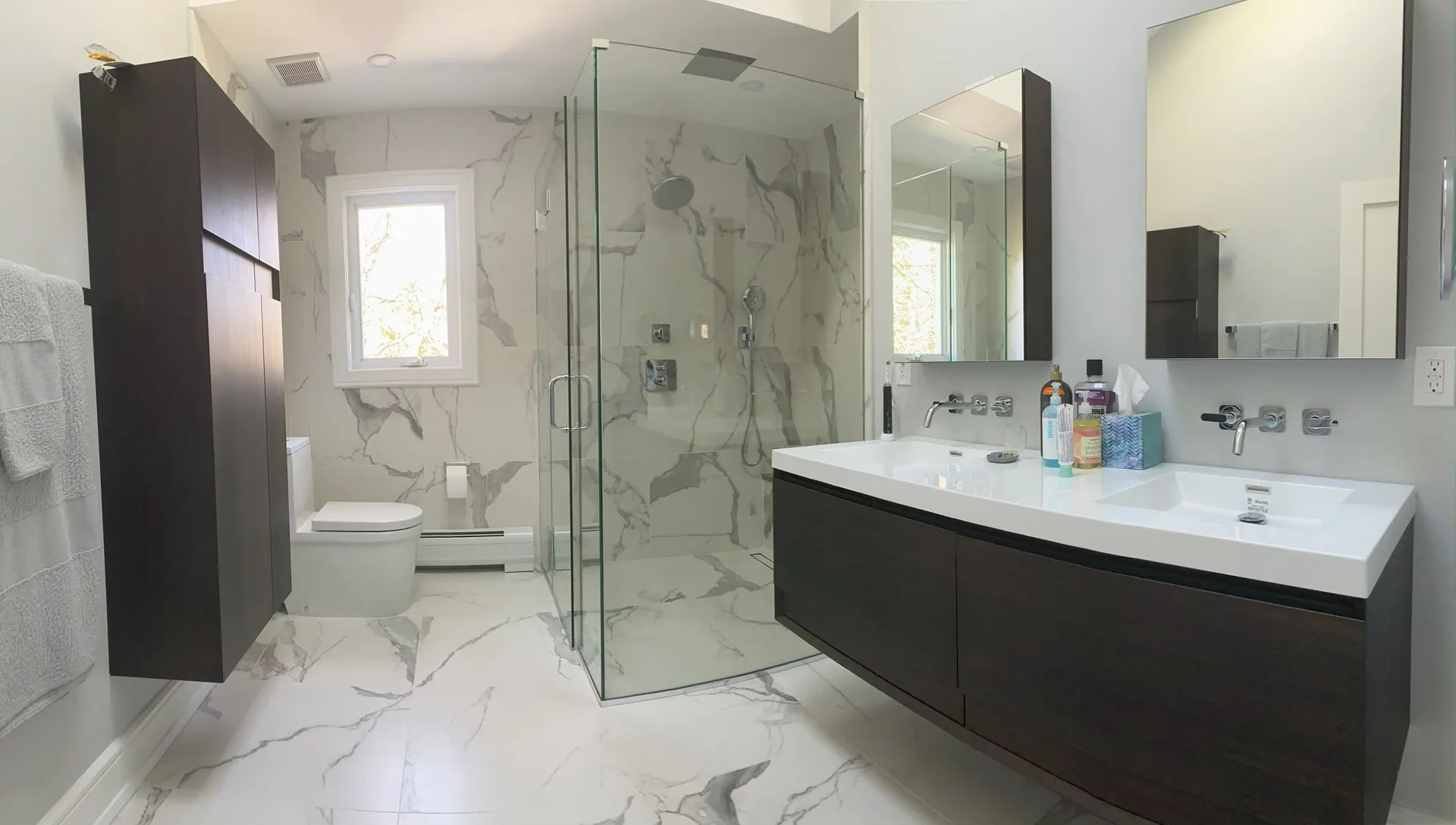 Bright luxury bathroom remodel with marble walls, glass shower and modern double vanity